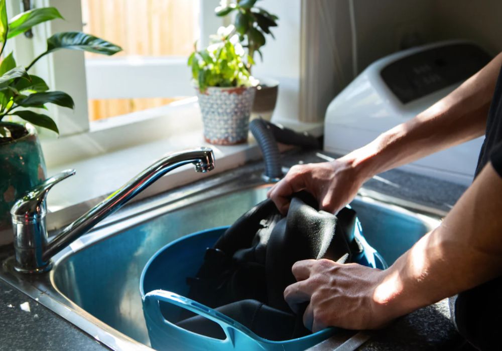 Wetsuit wassen in een wasbak